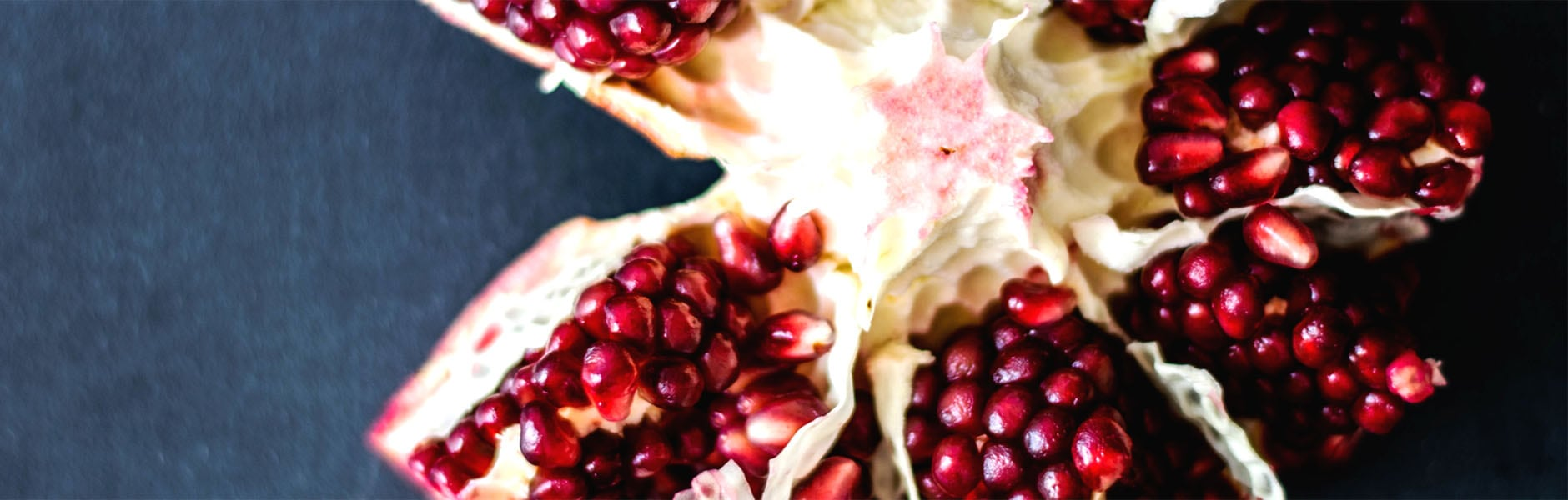 This pomegranate sitting on the table is one ingredient in this Bloom Naturals skin care collection that cures mild acne.