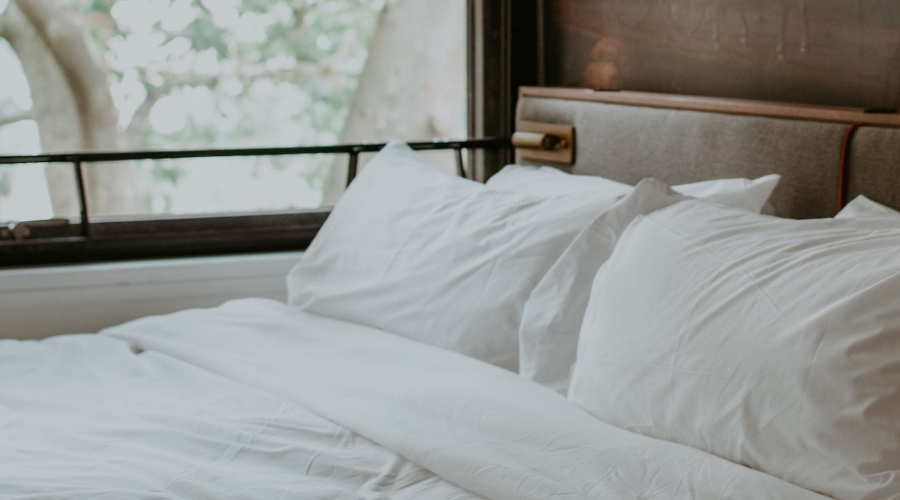 A beautiful bed next to a window, still may have toxins lurking in the pillows.